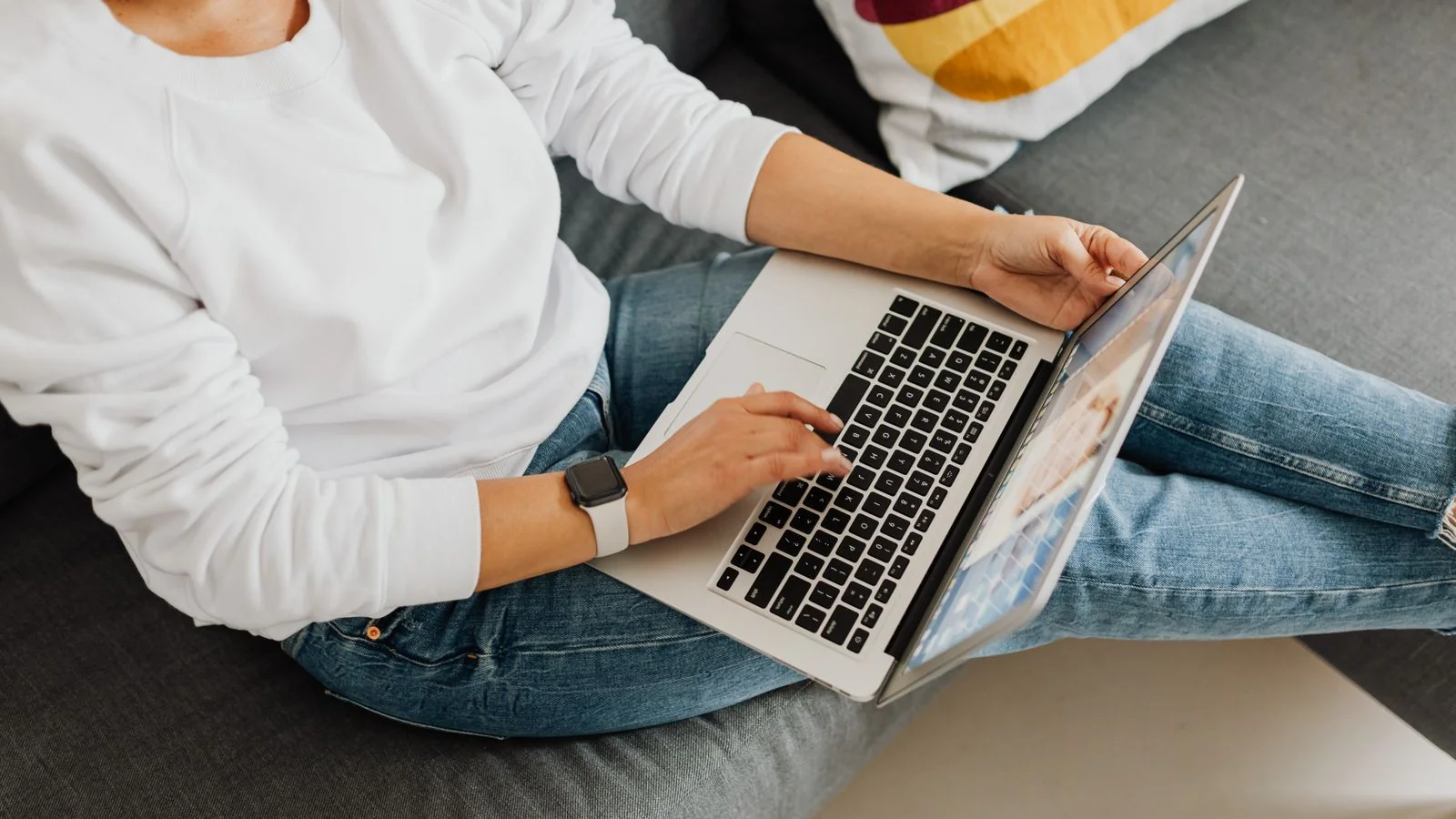A person on a laptop on a sofa, following a source link from an AI answer to the page behind it