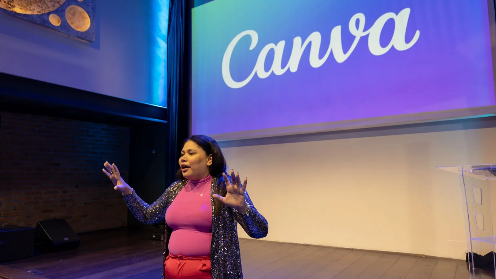 Woman presenting on stage in a modern auditorium to a seated audience