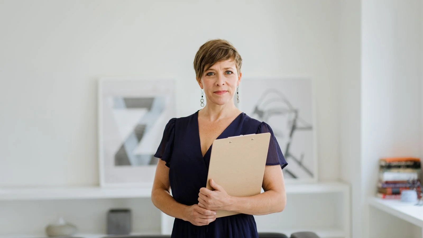 Confident woman with short hair holding a clipboard in an office setting