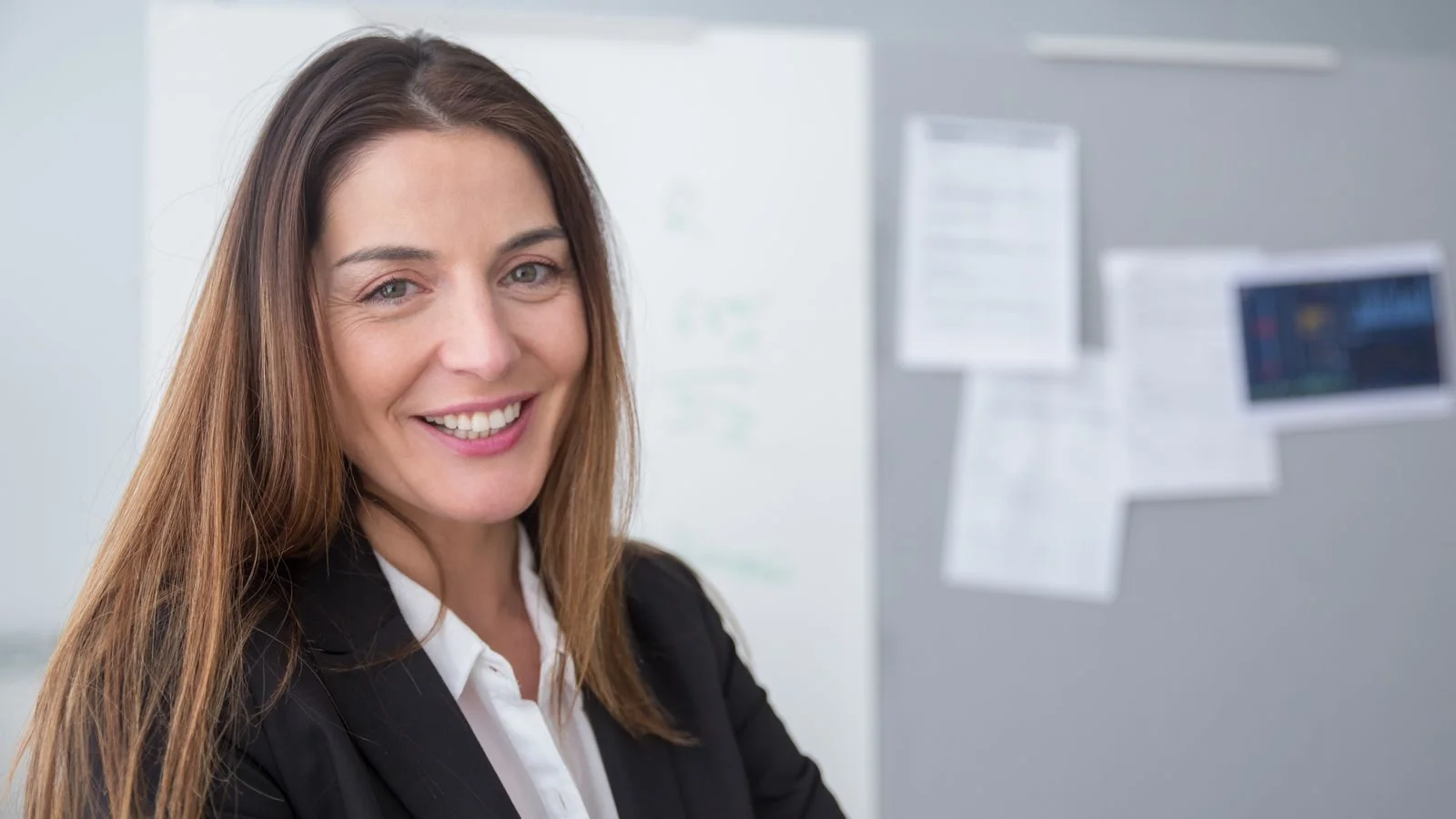 A professional smiling confidently in a modern office, projecting the reputation others already attach to their name