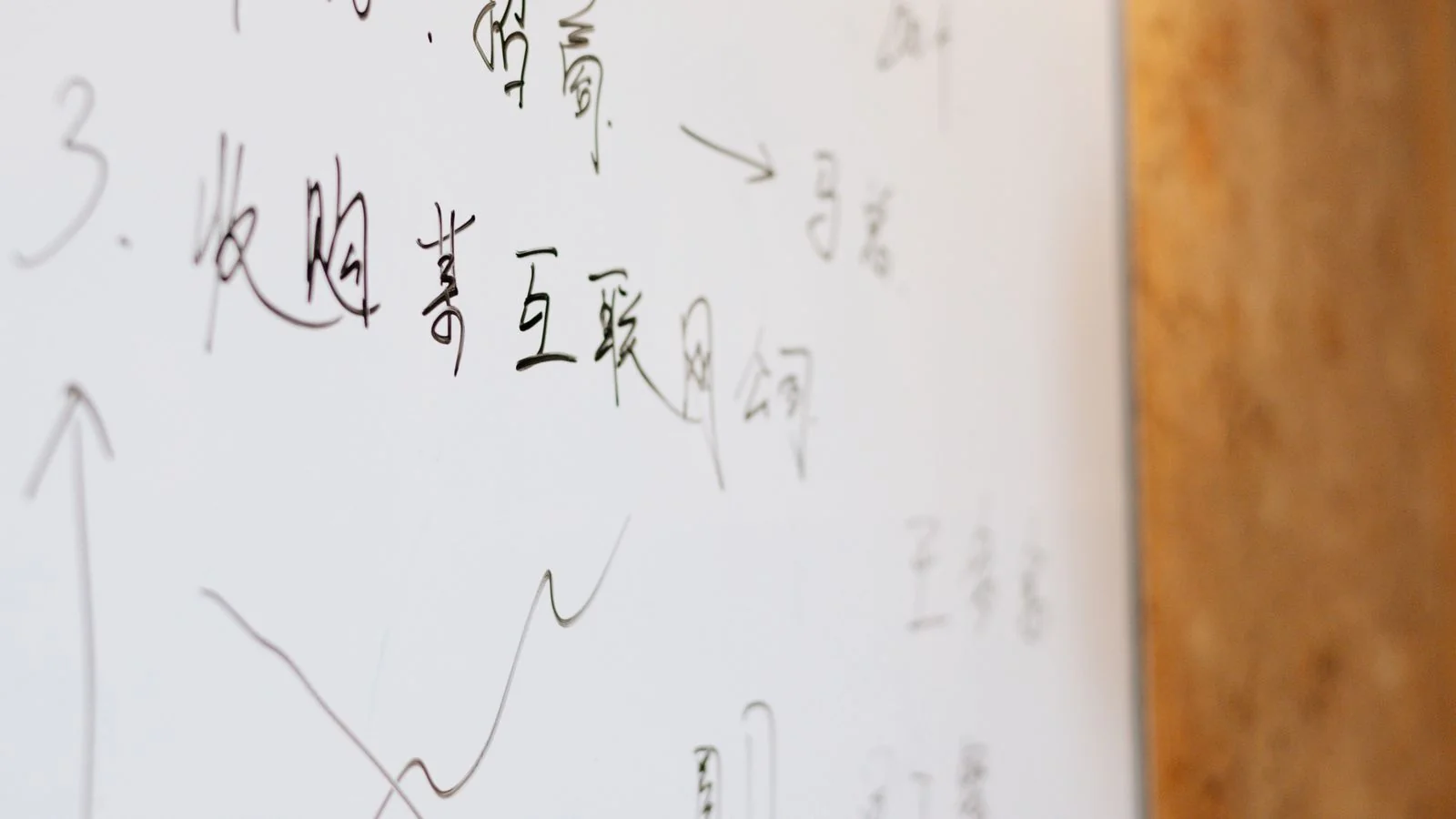 A hand writing strategy notes on a whiteboard, the act of compressing an idea to its shortest true form