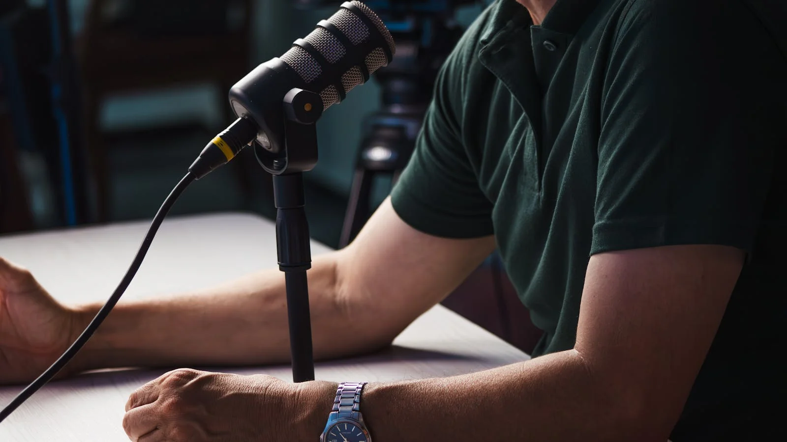 A person recording in a studio, leaning into the microphone mid-sentence