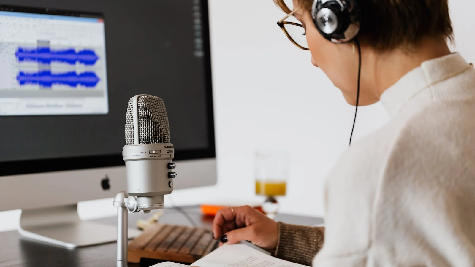 A creator recording at a microphone while reading from notes, keeping a consistent voice