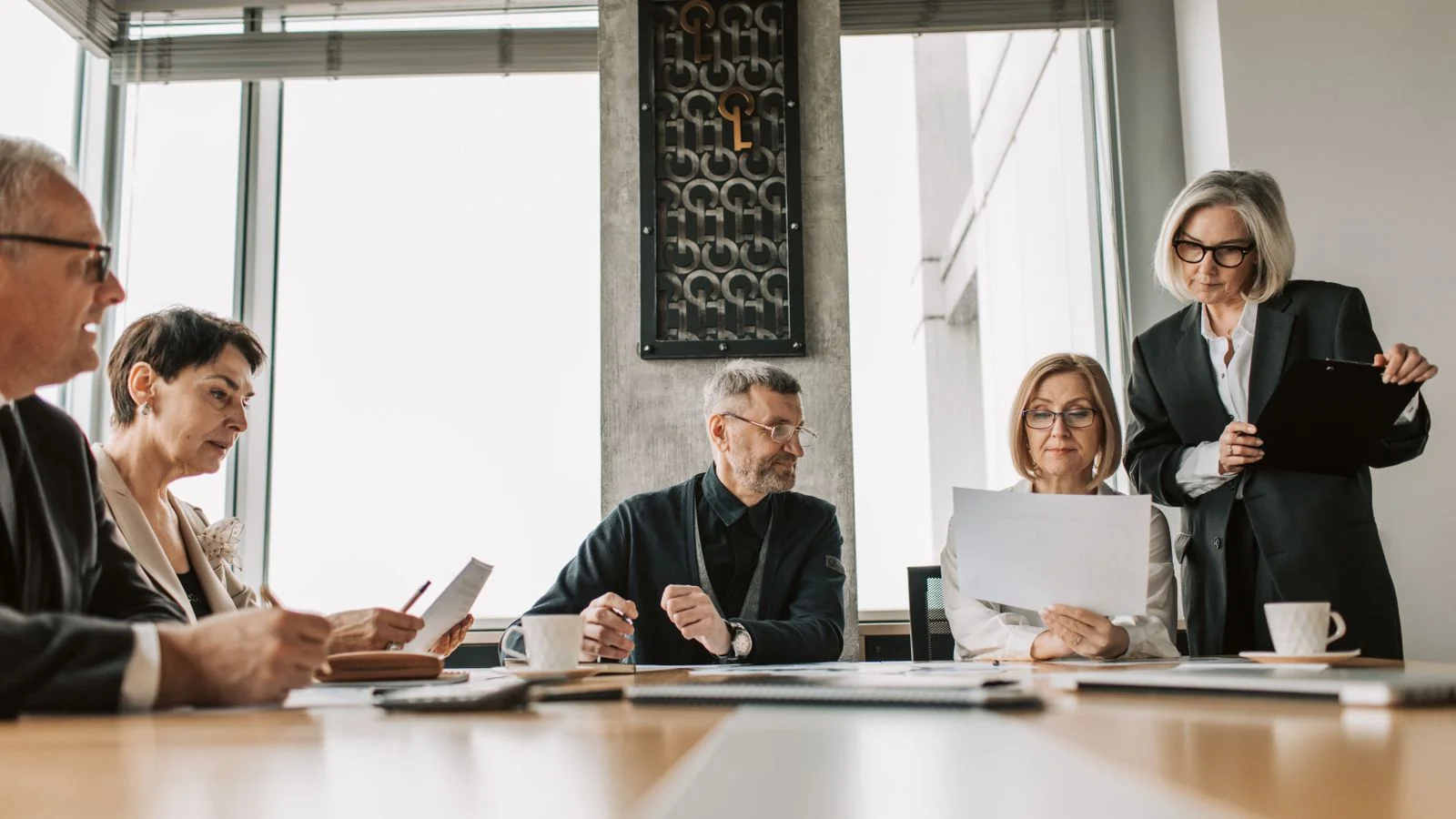 Executives reviewing documents together in a modern boardroom meeting.
