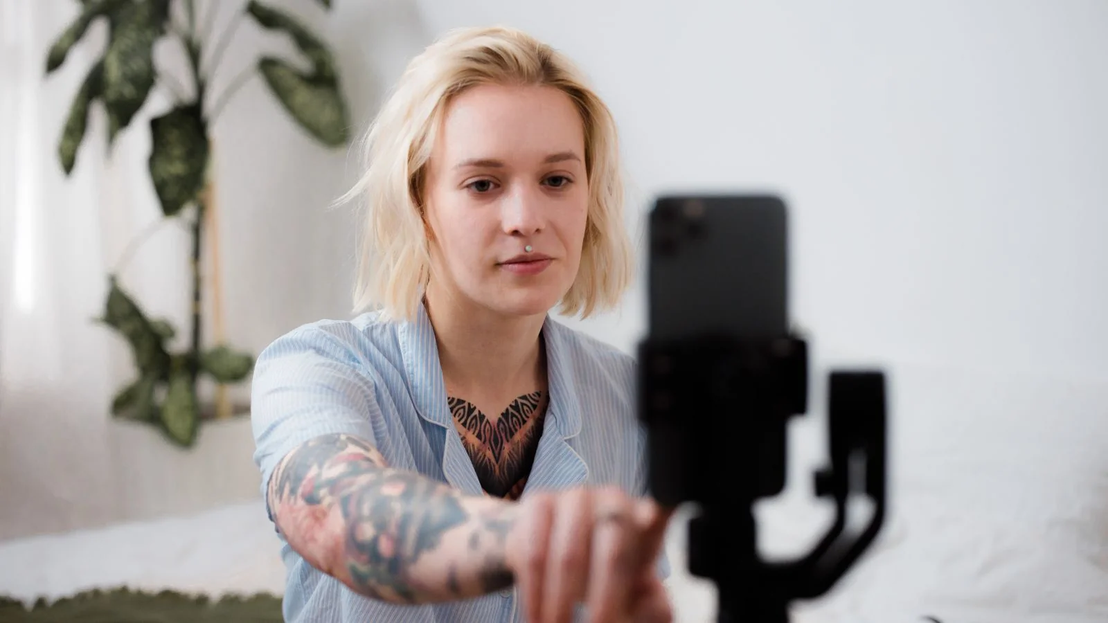 A person setting up a smartphone on a tripod to film content at home.