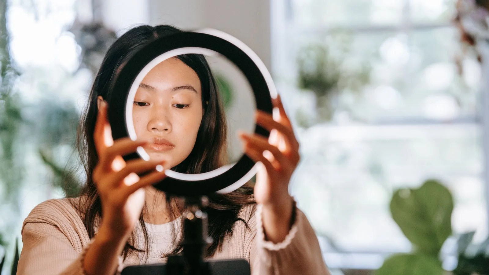 A woman setting up a ring light at home, more production than most coaches actually need