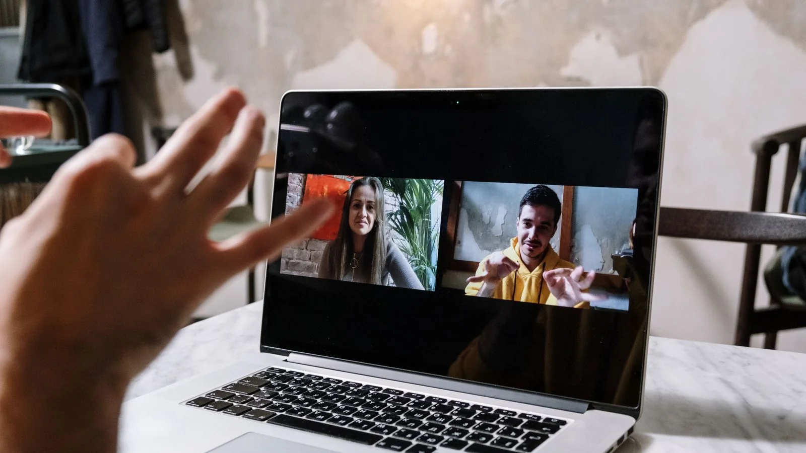 Hands gesturing during a video call shown on a laptop screen, the weekly live session that many memberships depend on