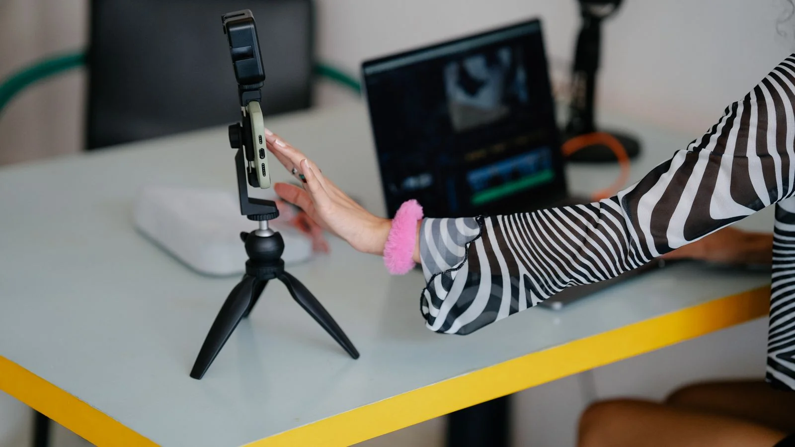 Loan officer setting up a smartphone on a tripod to record a short video at her desk.