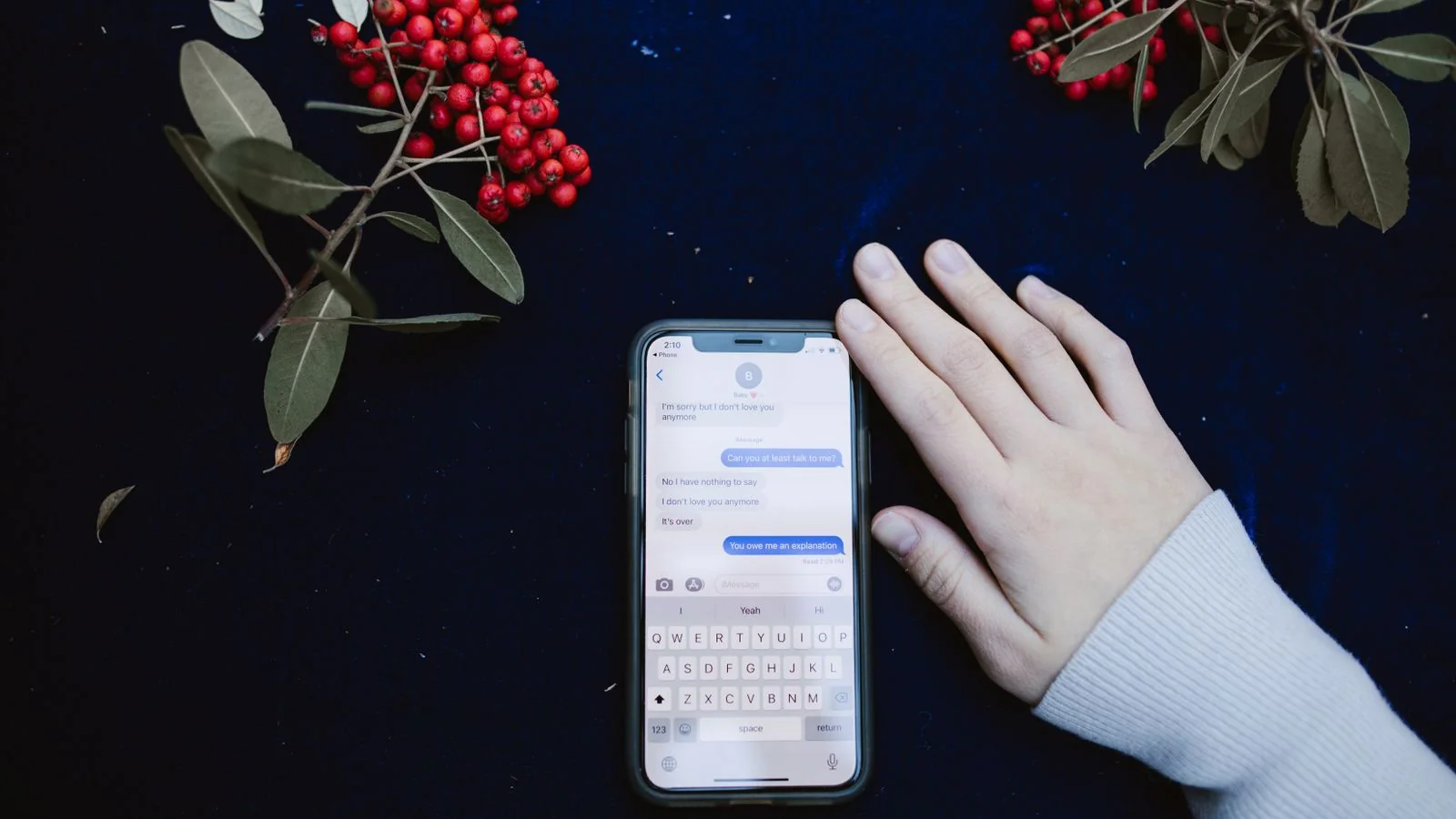A hand beside a smartphone showing a text-message conversation.