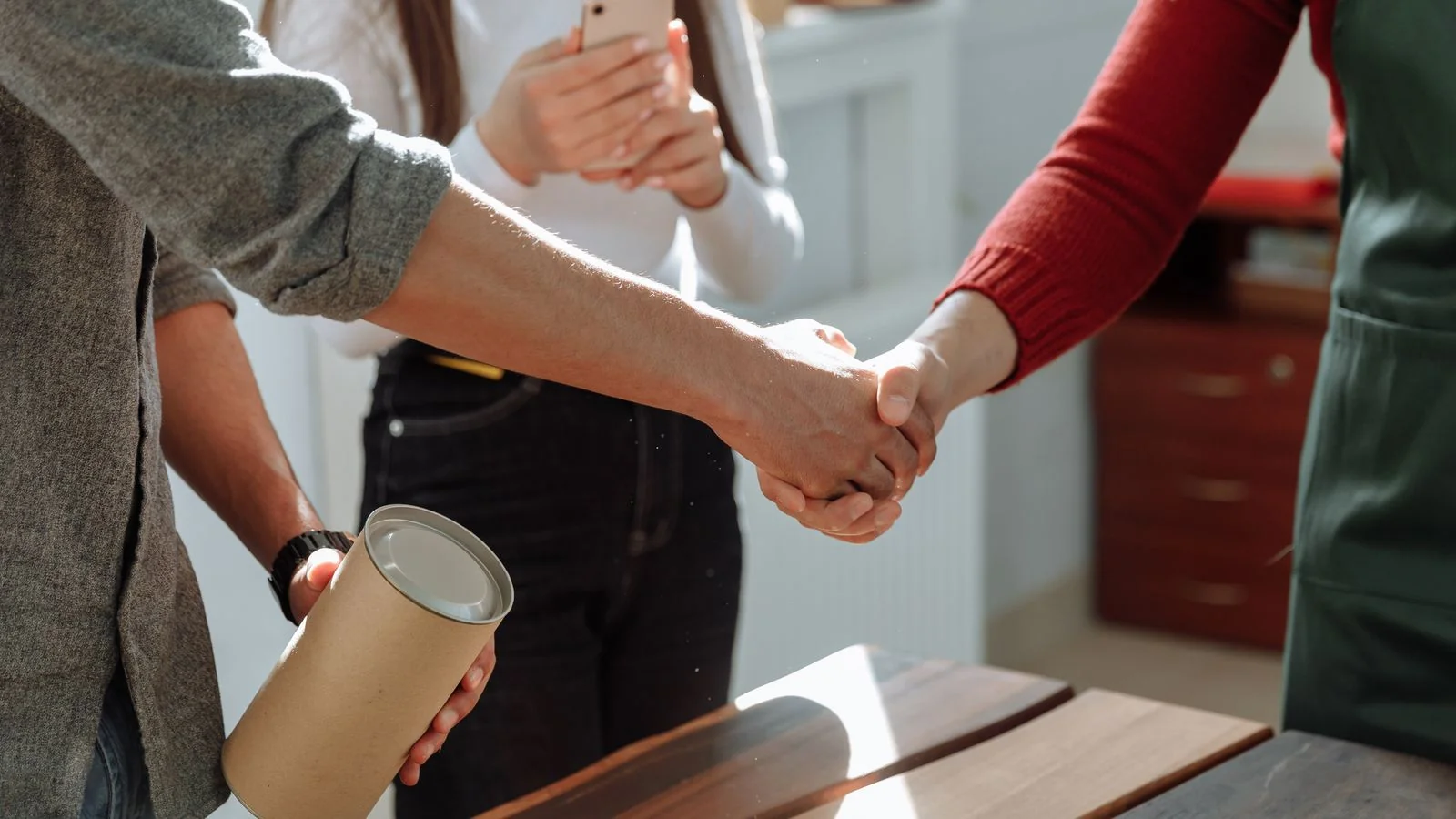 Three people sealing a deal with a handshake, where a trusted name closes the paving job.