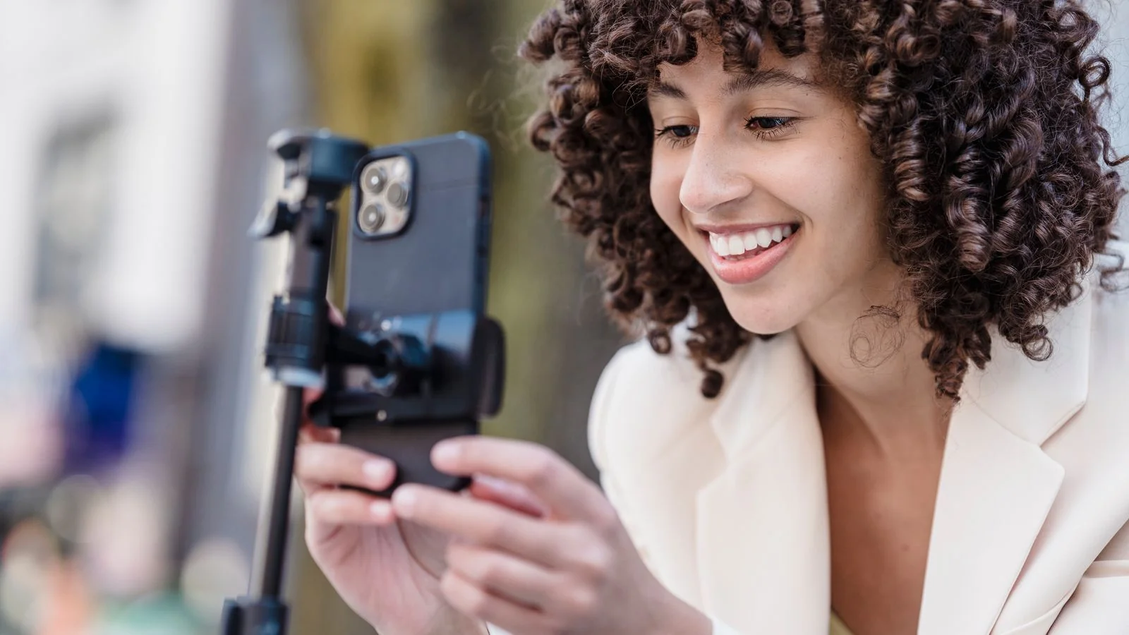 A person in business attire recording a short video on a smartphone mounted on a tripod.