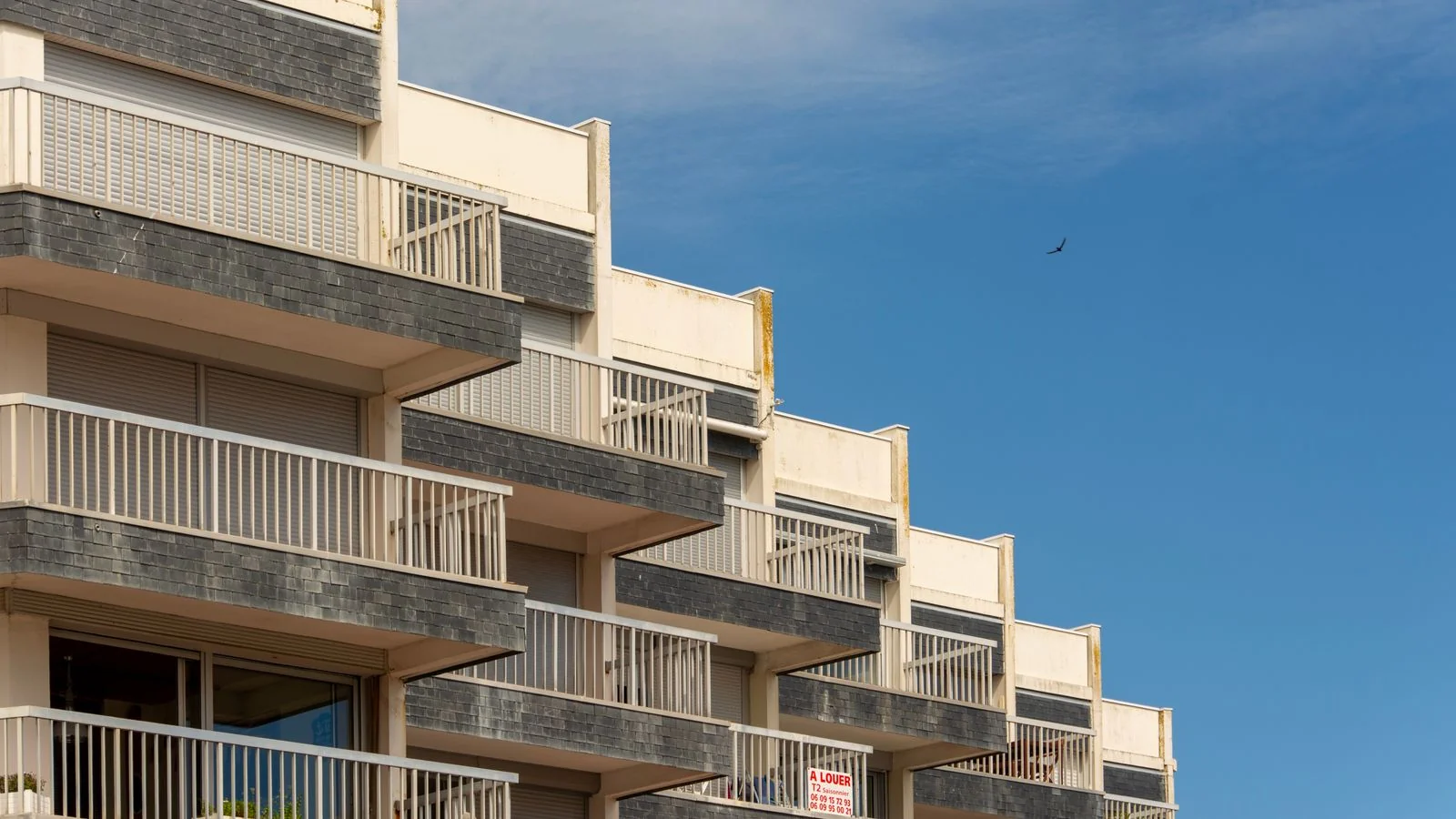 Modern apartment building with balconies under a clear sky, the kind of specific asset a sponsor should name rather than count.