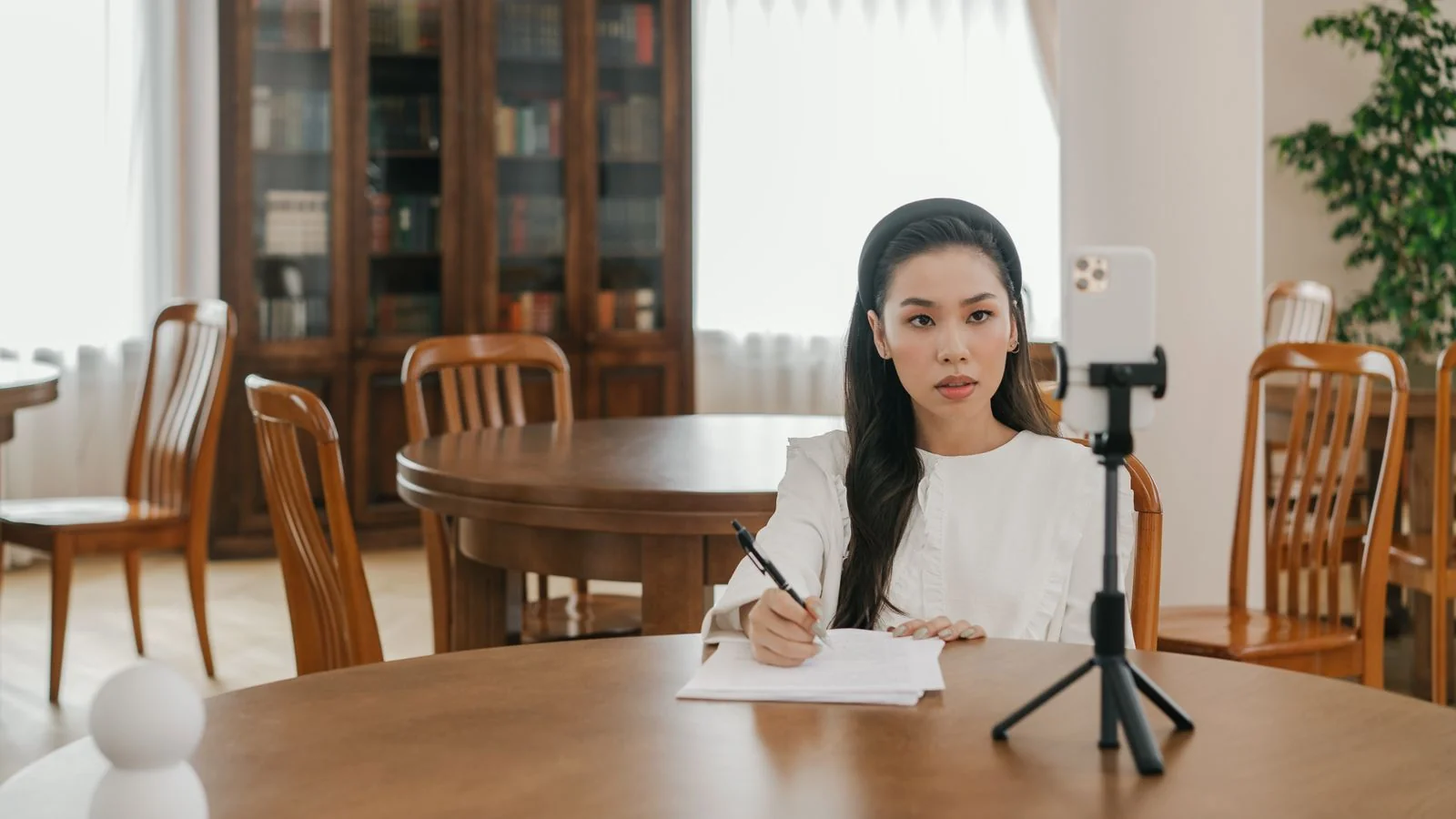 A recruiter recording video content with a phone on a tripod in a home office.