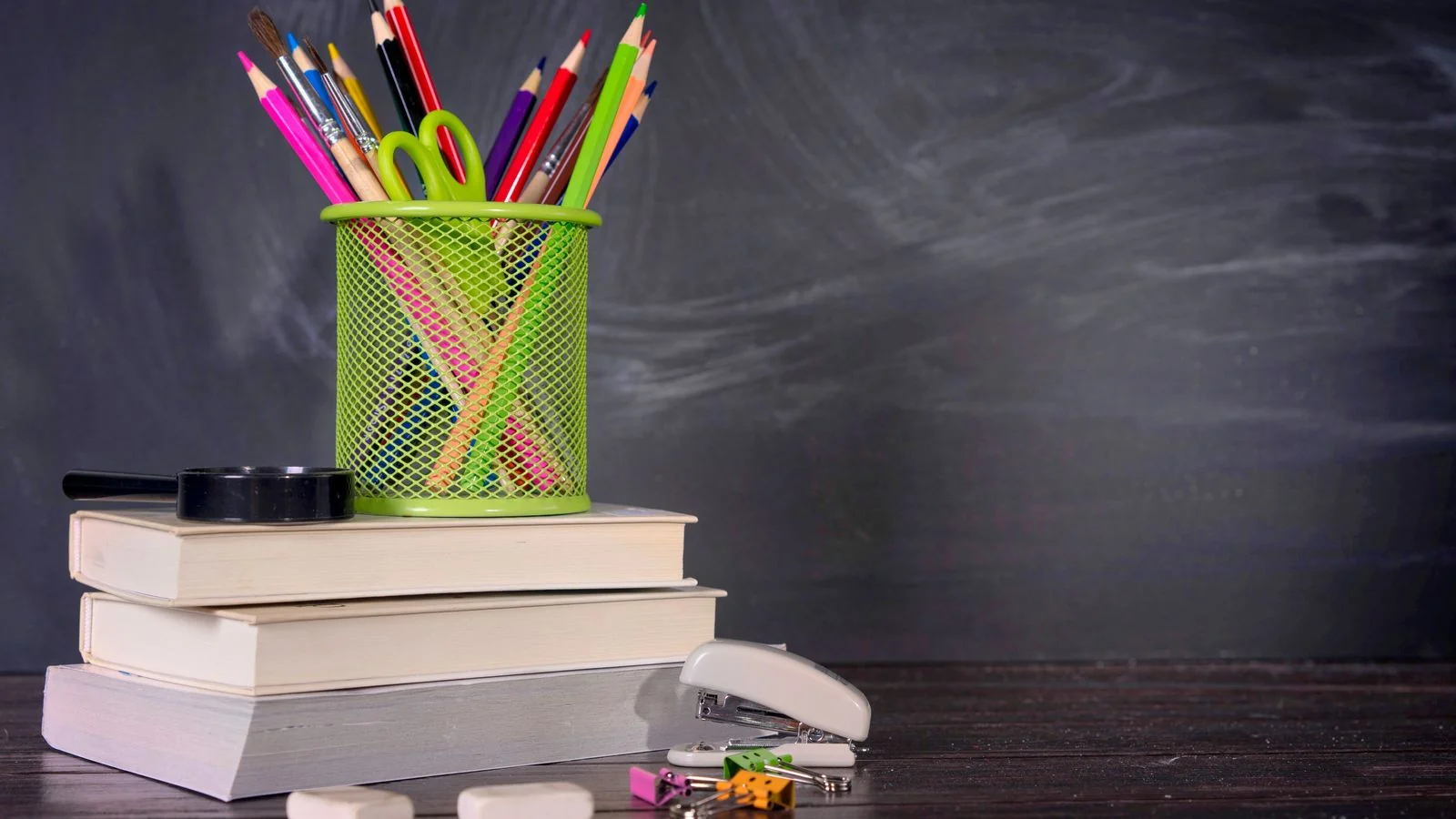 A stack of thick textbooks with pencils and a notepad beside them