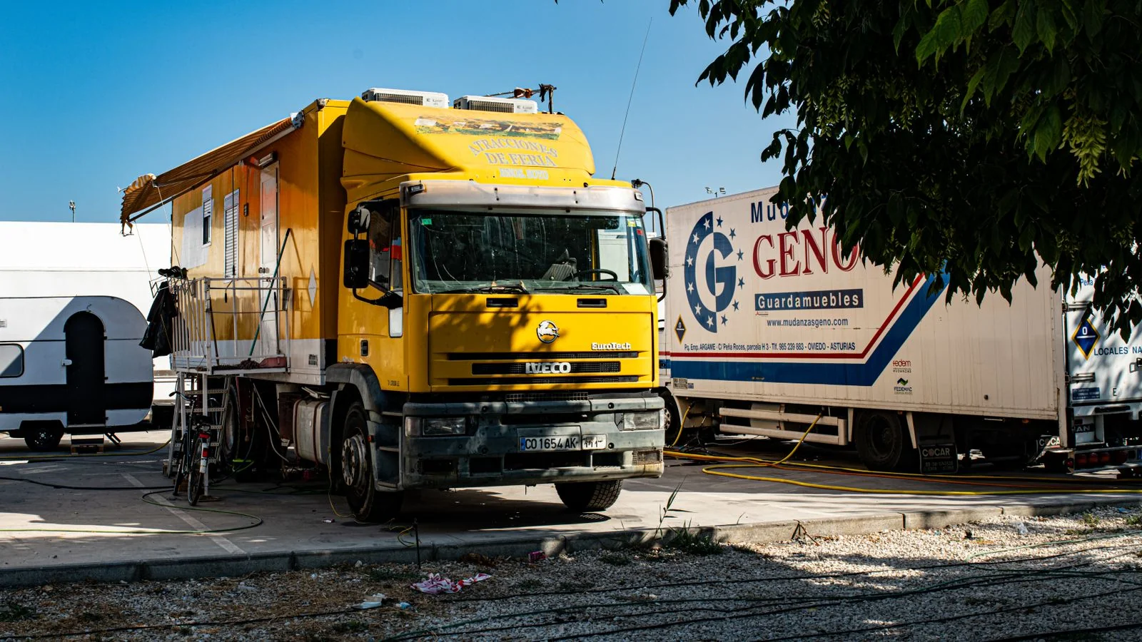 A work truck parked outdoors near trees on a bright, sunny day.