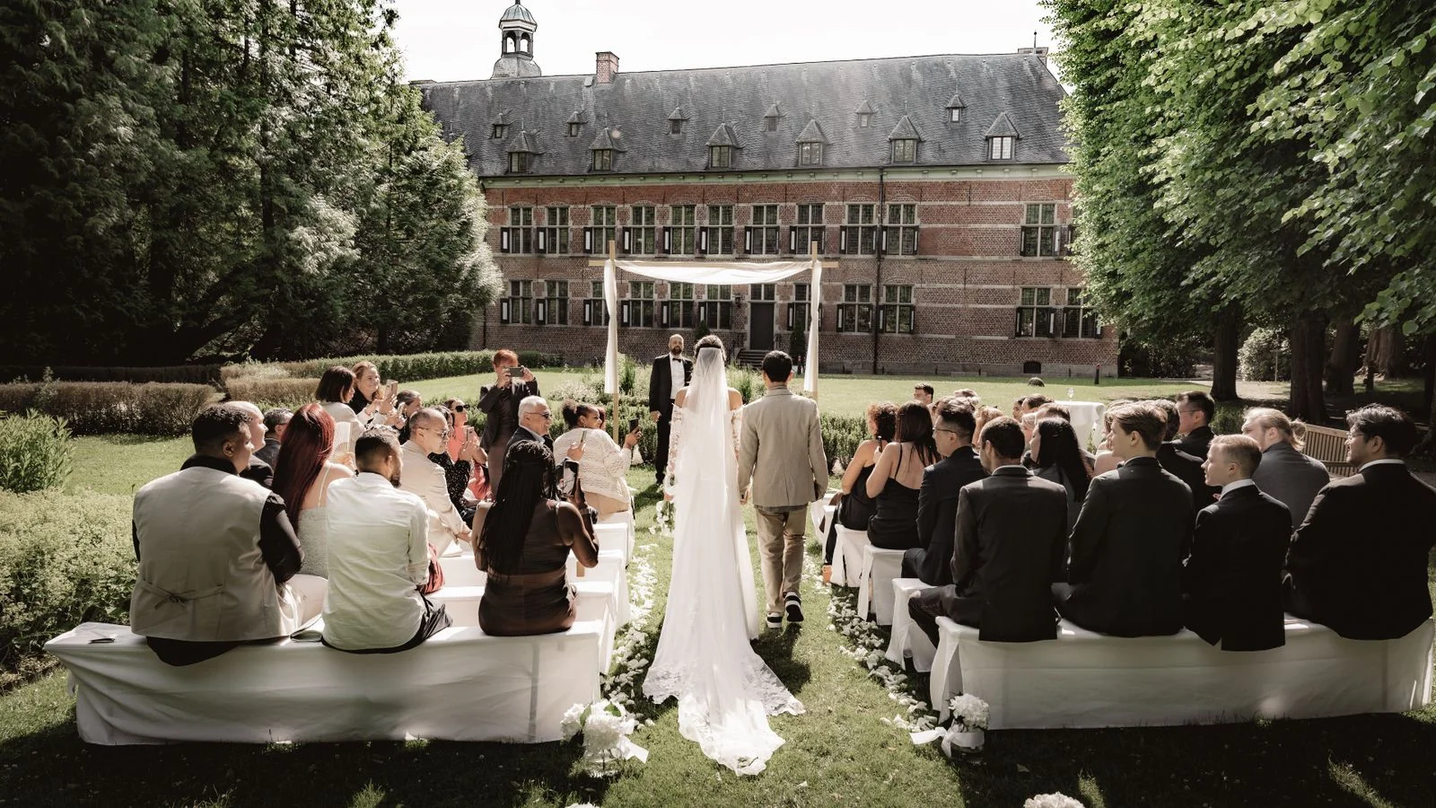 An outdoor ceremony with guests seated in front of a historic building, the version that depends entirely on somebody's weather call.
