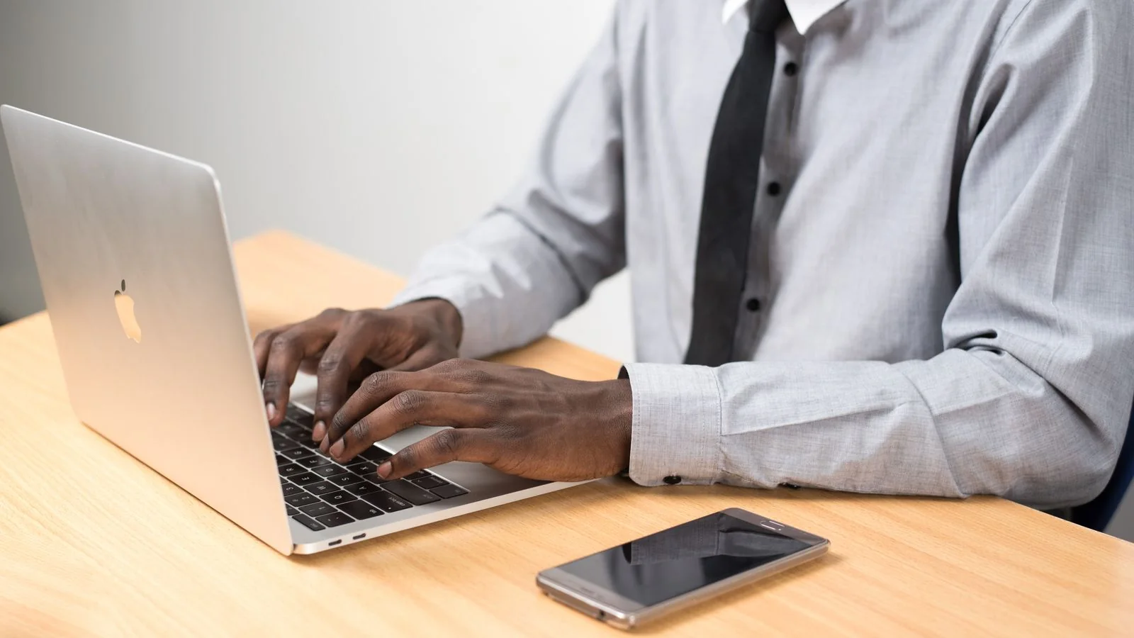 A person working on a laptop and phone at a desk, running the daily loop of posting and engaging