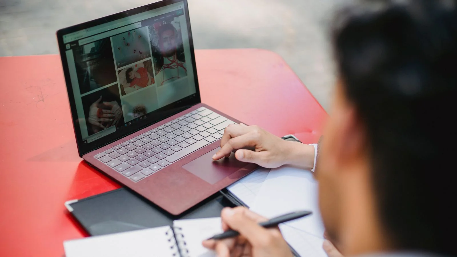 A person writing notes beside a laptop, defining their point of view before any tool touches it