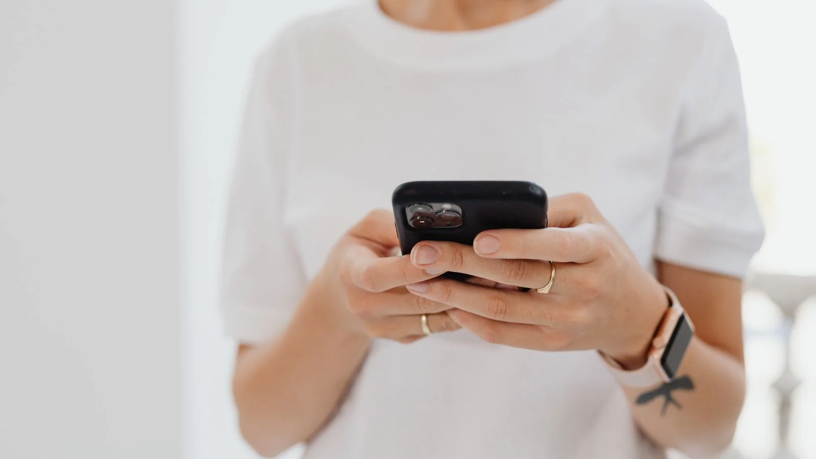 Adult tapping a smartphone touchscreen, the way most customers now answer a text review request