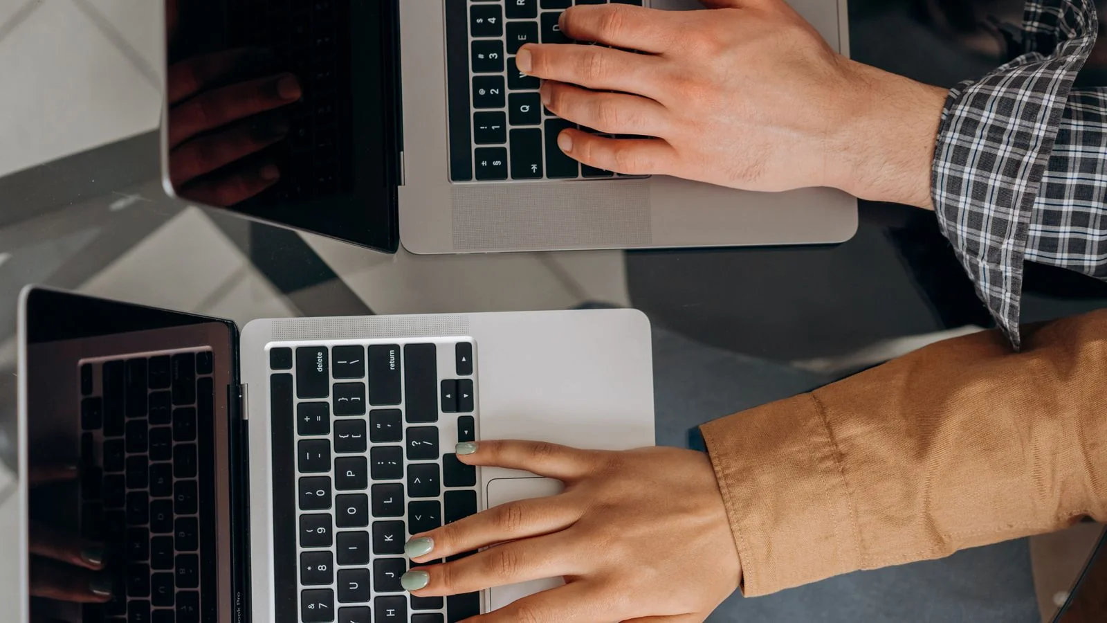 Two people working on laptops together, comparing review platform dashboards side by side