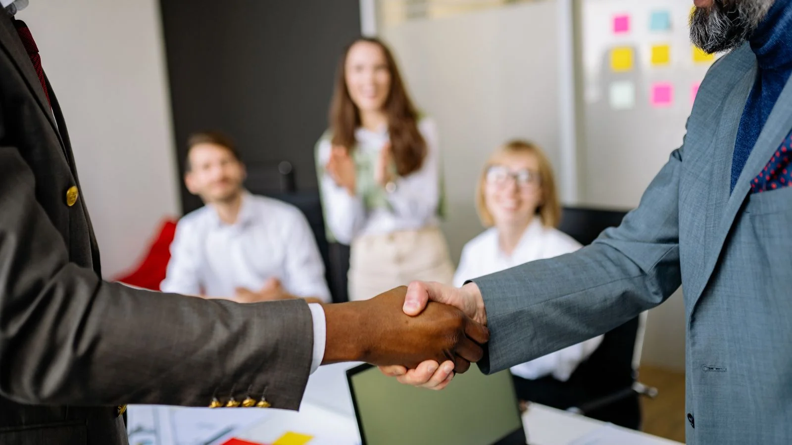 Two professionals shaking hands at a desk, the relationship business at the core of the PR industry