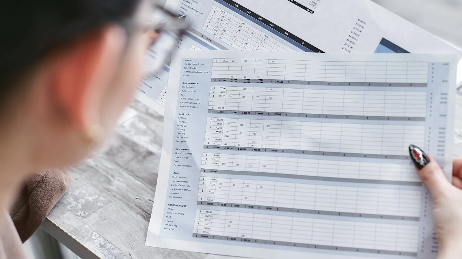 Hands holding a financial spreadsheet review document at an office table, the surface where PR ROI is judged