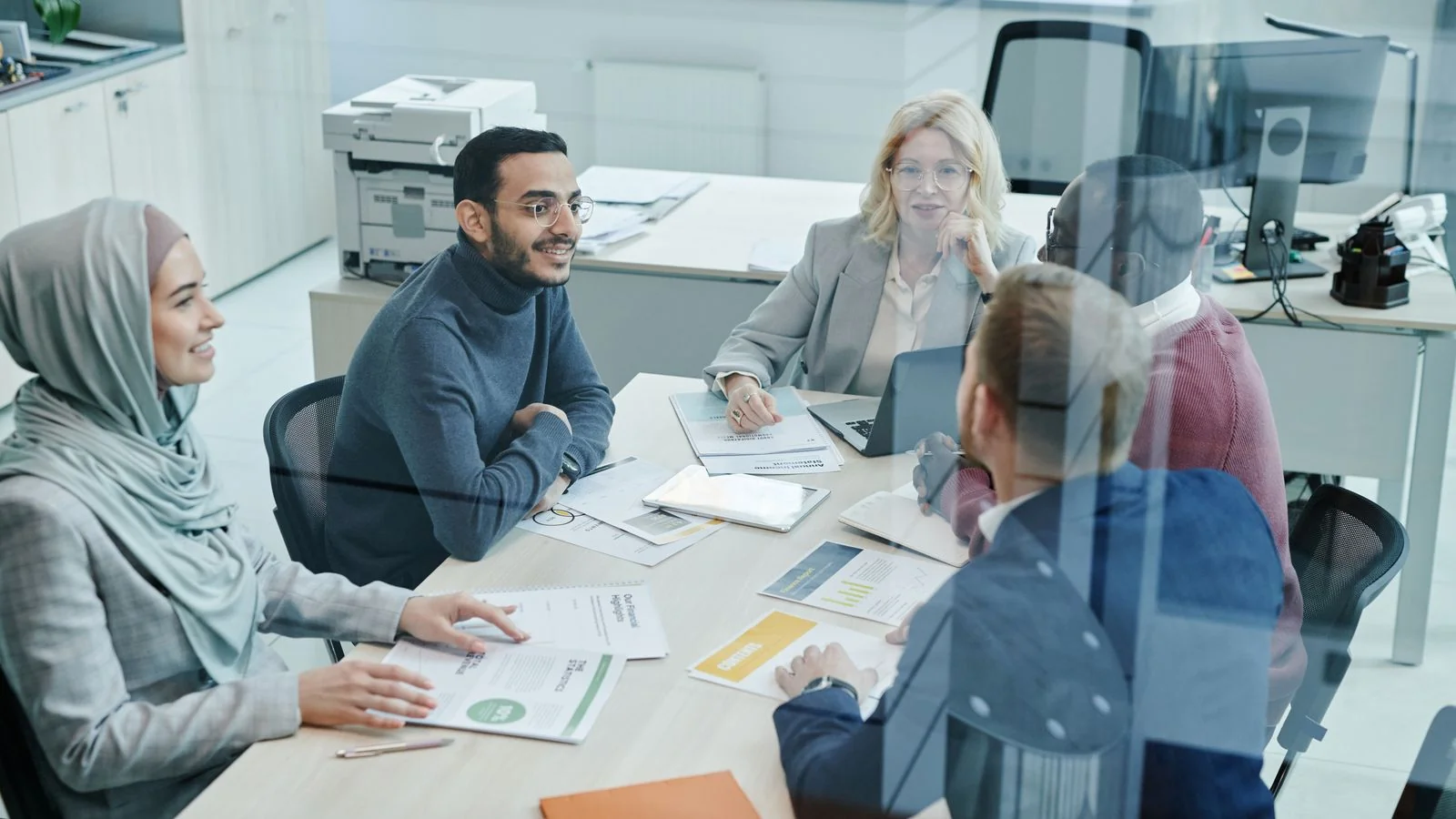 A team gathered around a laptop reviewing a distribution plan before hitting send