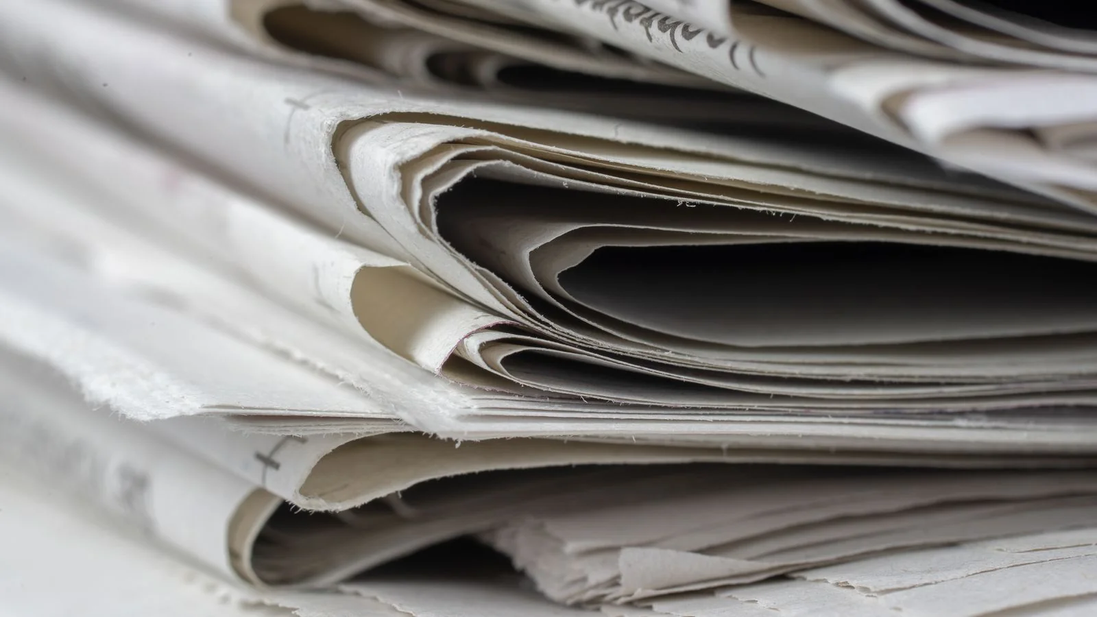 A close-up of stacked newspapers, standing in for the volume of syndication pickups