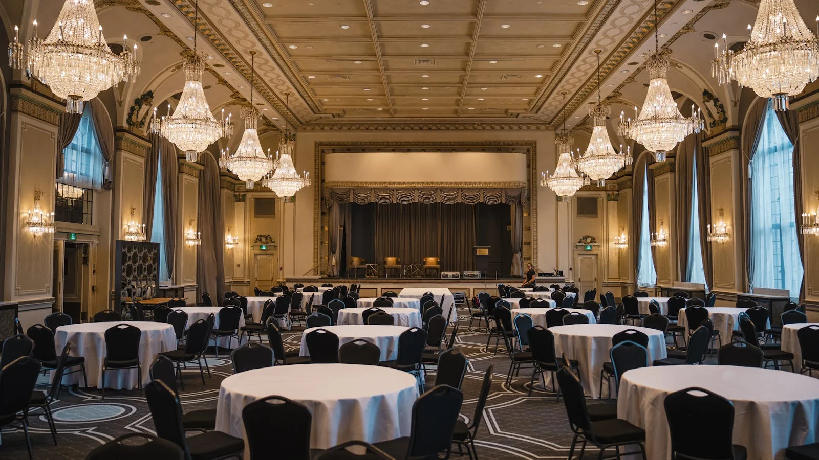 Empty banquet hall with rows of decorated tables set for an upcoming press event and media reception