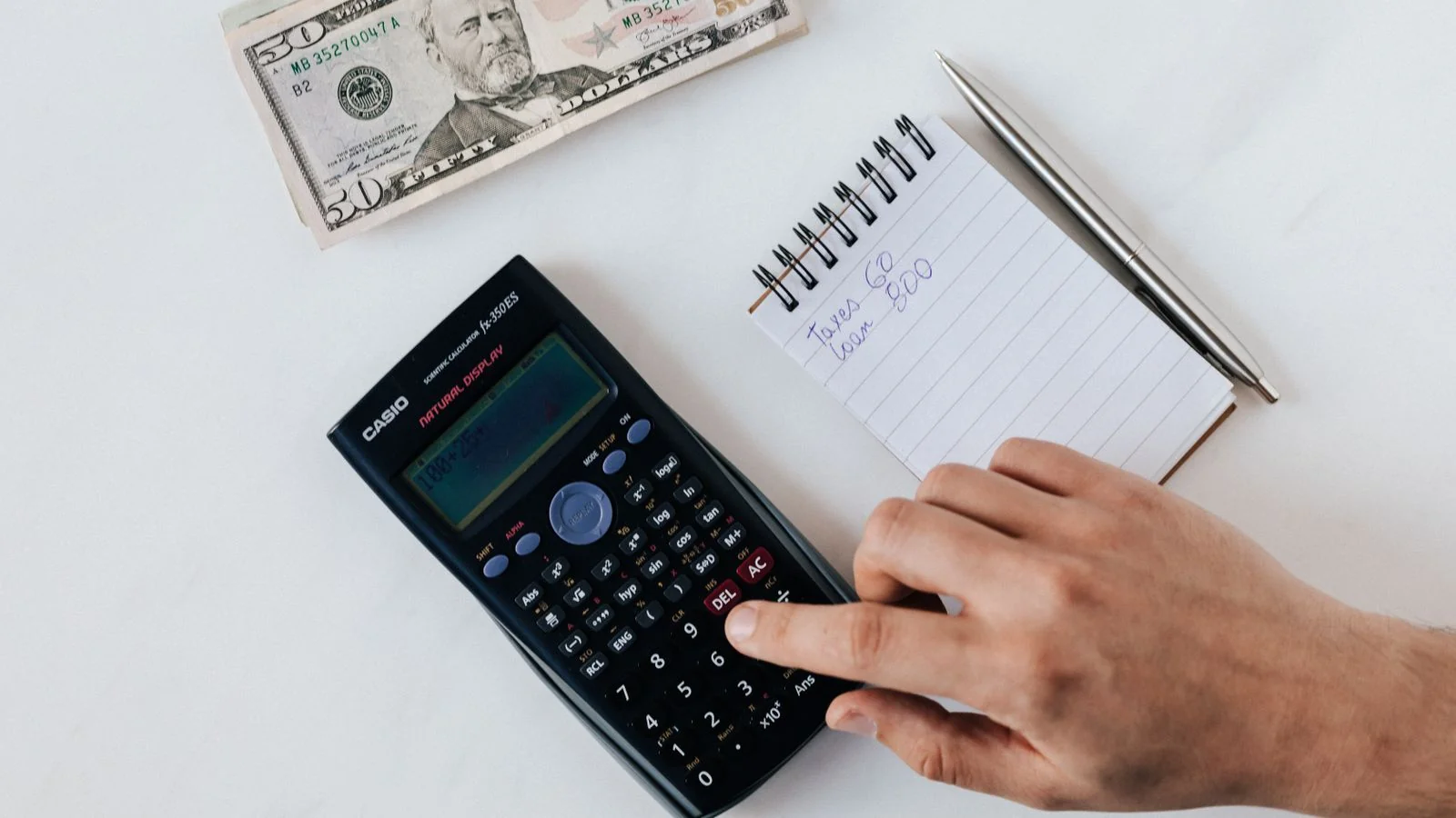 An accountant calculating figures with a calculator beside stacks of banknotes