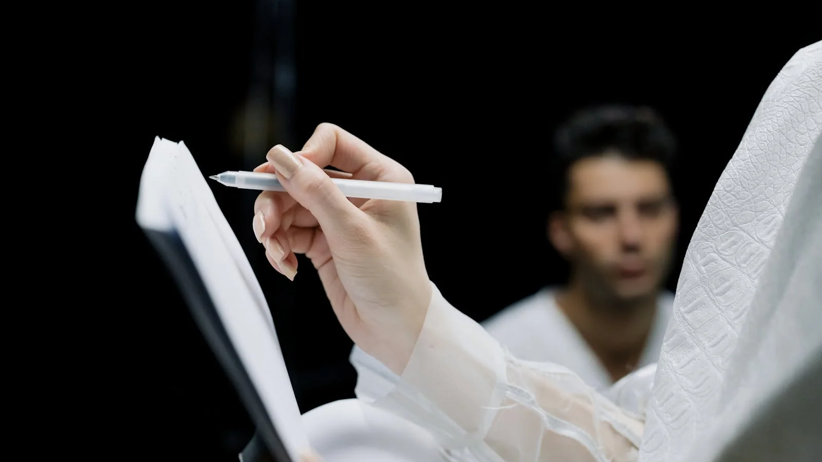 A hand writing notes on a notepad, the groundwork of any press release.