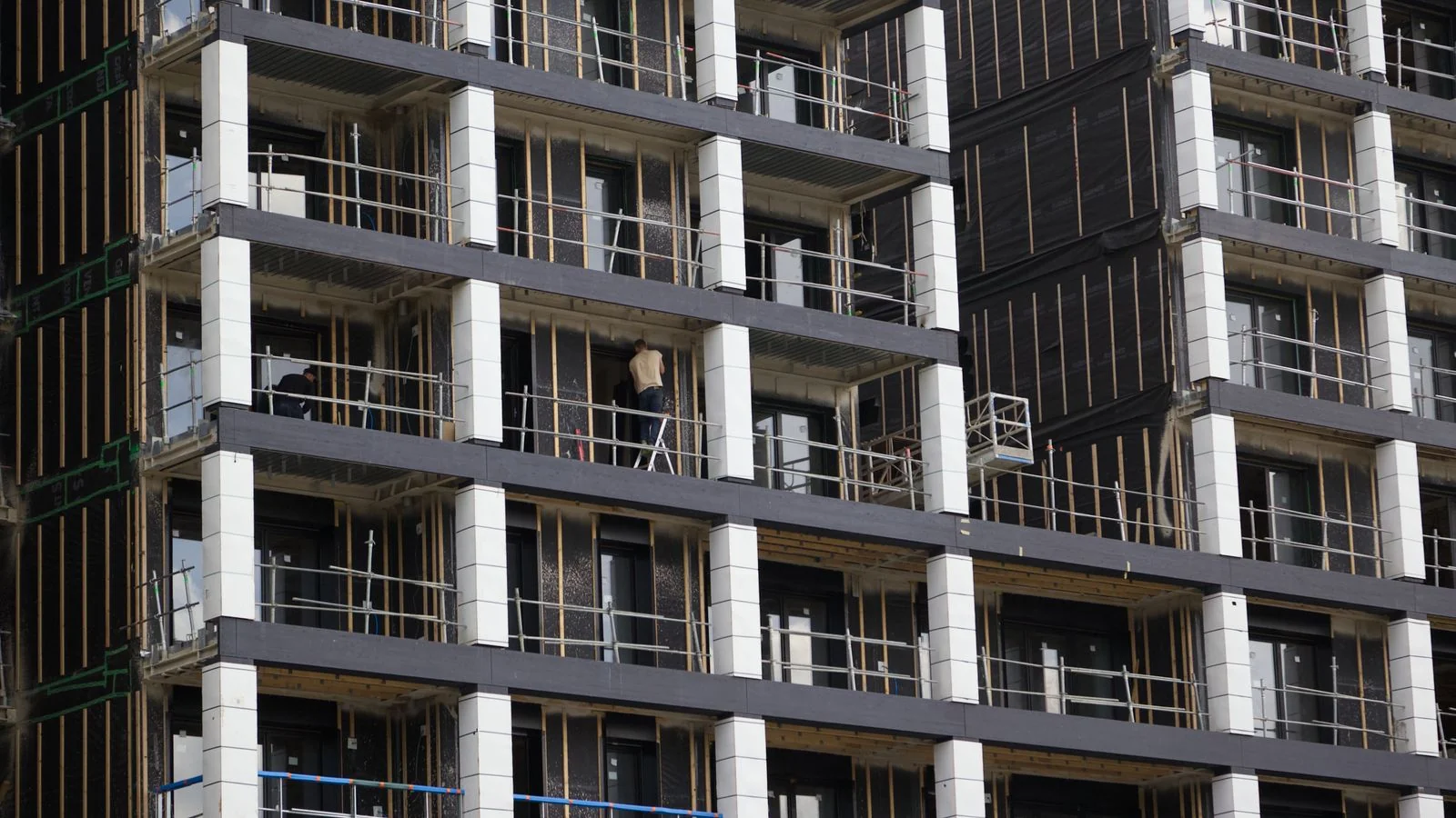 A modern high-rise under construction with visible scaffolding and workers on site