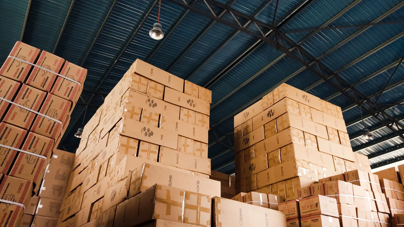 Stacked shipping boxes in a small warehouse, the fulfilment stage every campaign promise lands on