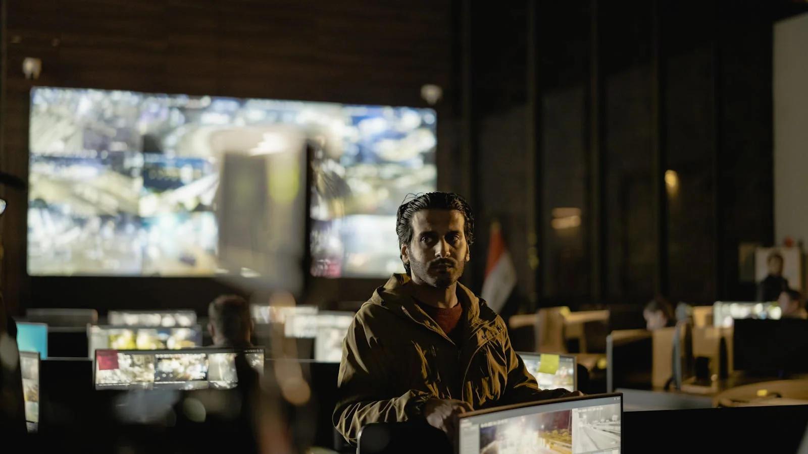 Diverse security operations team monitoring live surveillance and threat feeds inside a darkened control room
