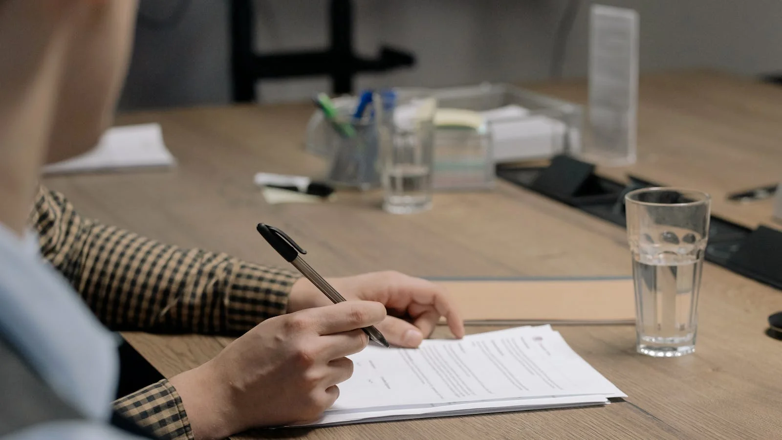 A person signing a document at a desk, the final approval step before a release goes out.