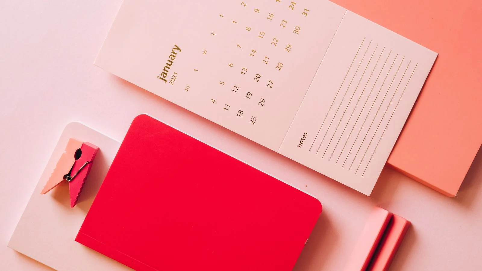 Multicolored calendar pages and planning notebooks laid out on a desk, mapping a seasonal press timeline