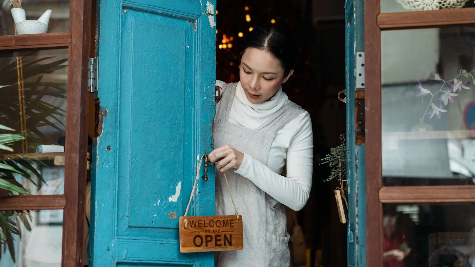 Shop owner adjusting a sign on the door of a small retail unit before opening hours