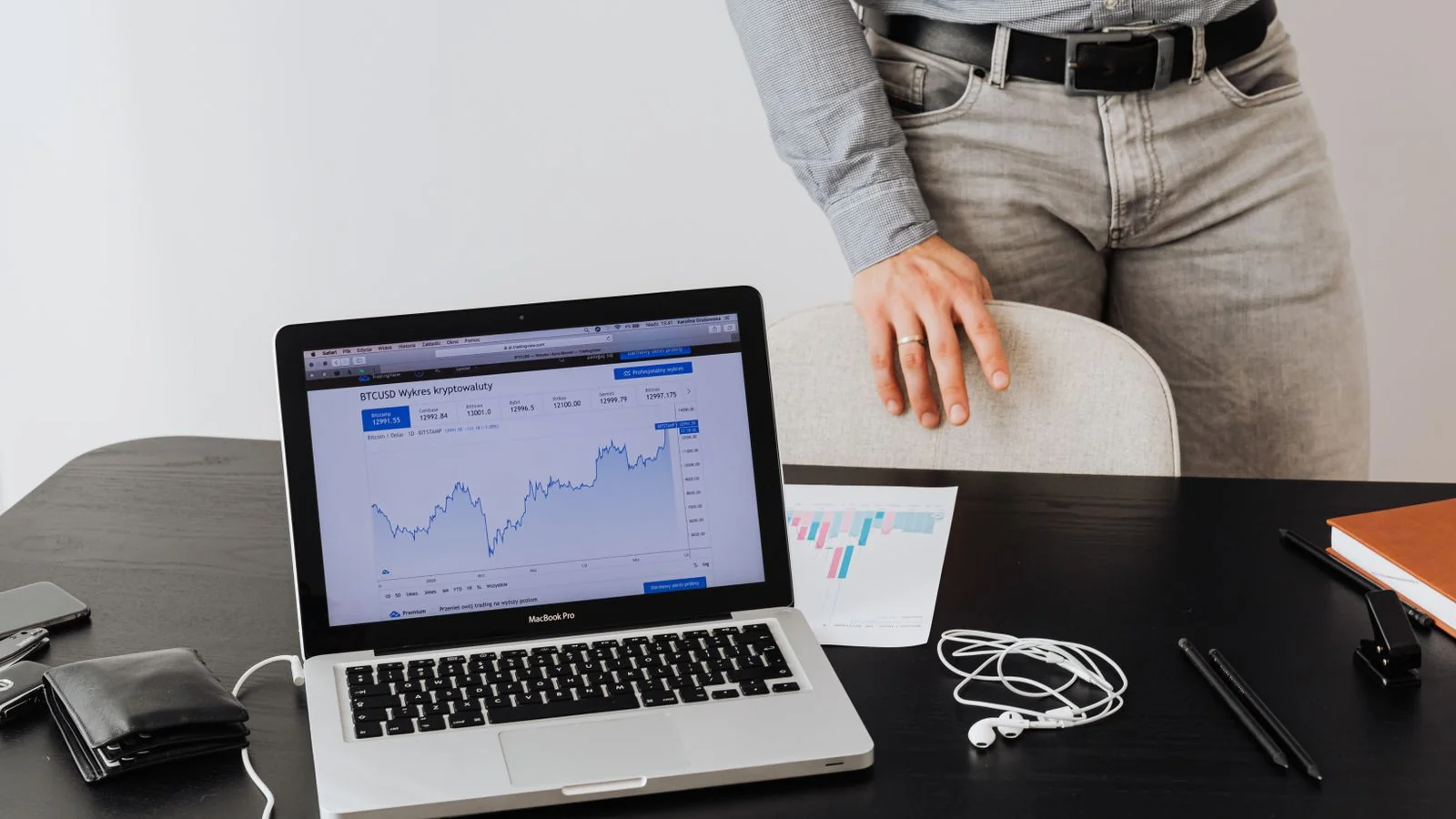 Businessman standing beside a laptop that displays financial data charts, reviewing performance numbers