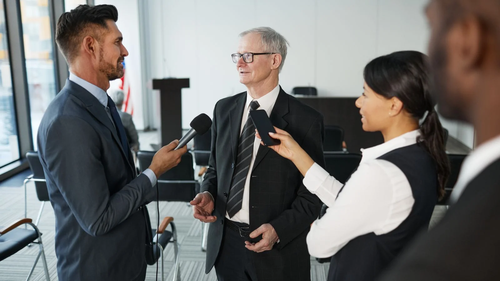Two journalists interviewing a senior executive in a formal office, the kind of exchange a strong quote imitates