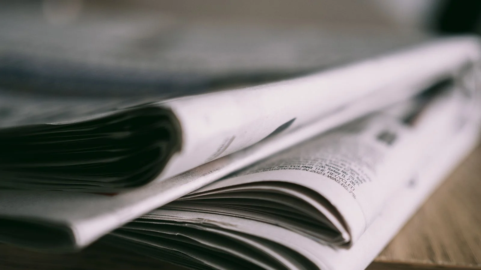 A stack of folded newspapers on a wooden table, the destination a strong press release is aiming for