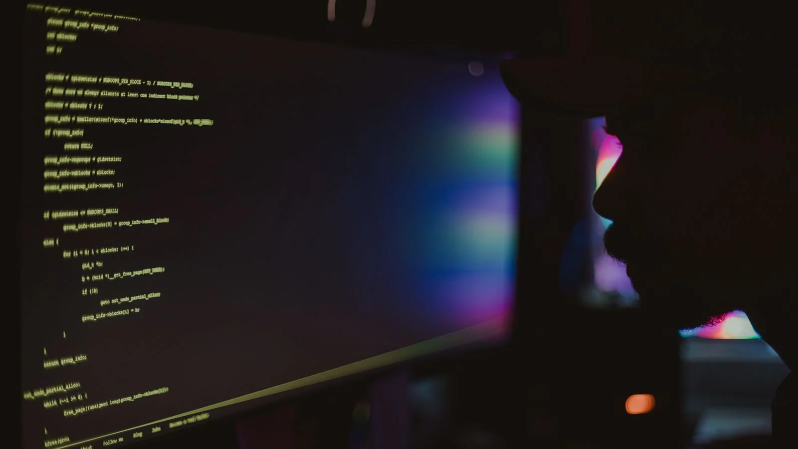 Silhouette of a developer looking at lines of code on a dark screen