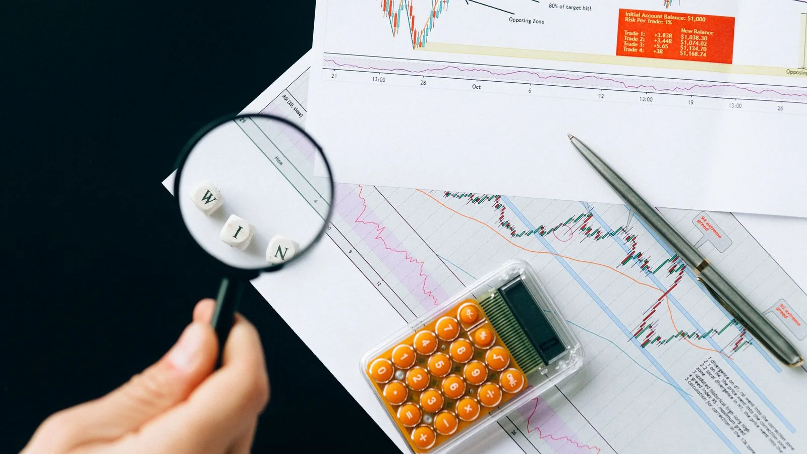 Magnifying glass over printed financial charts and figures on a desk