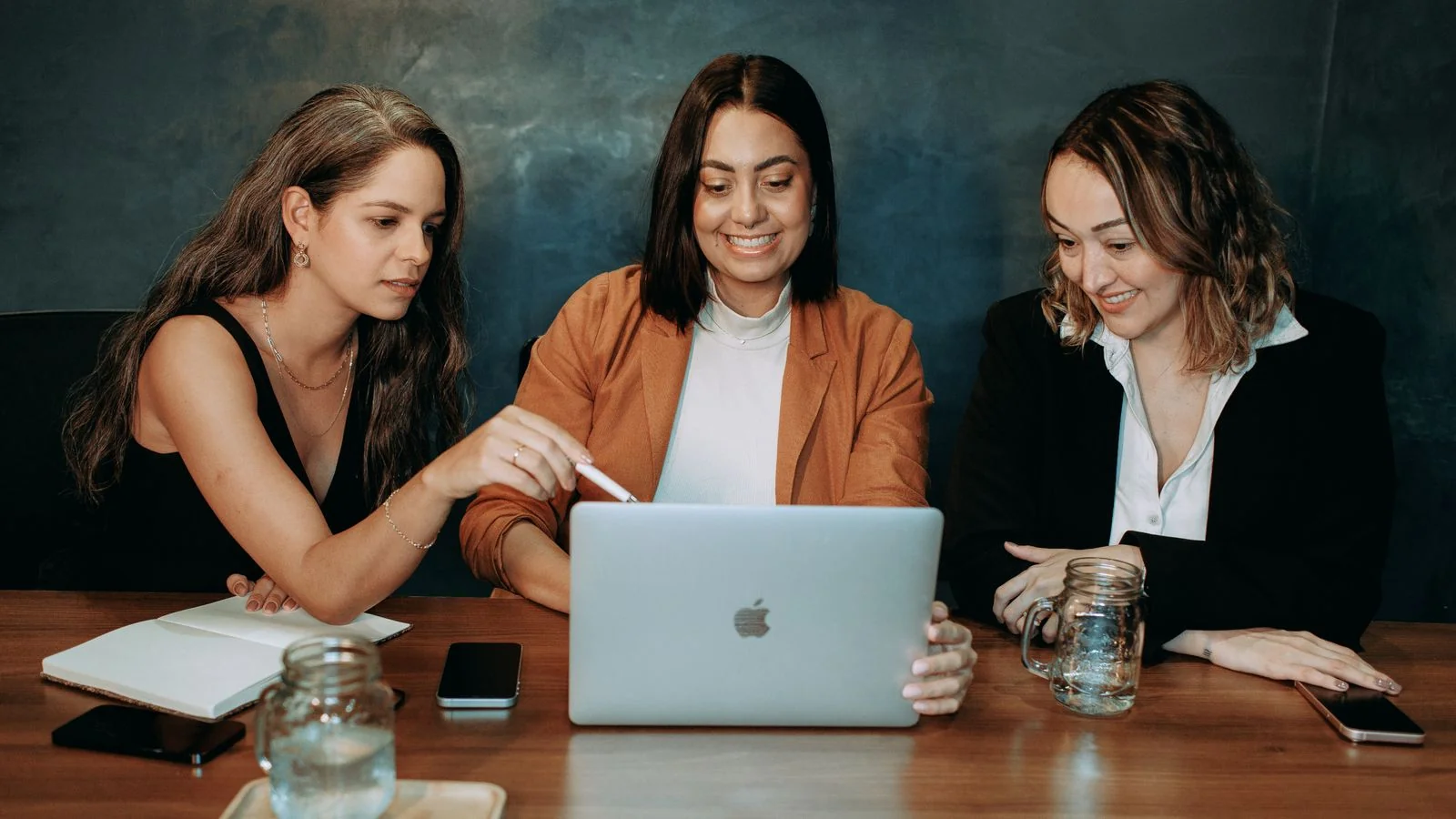 Colleagues collaborating around a laptop, the multi-person coordination an agency brings