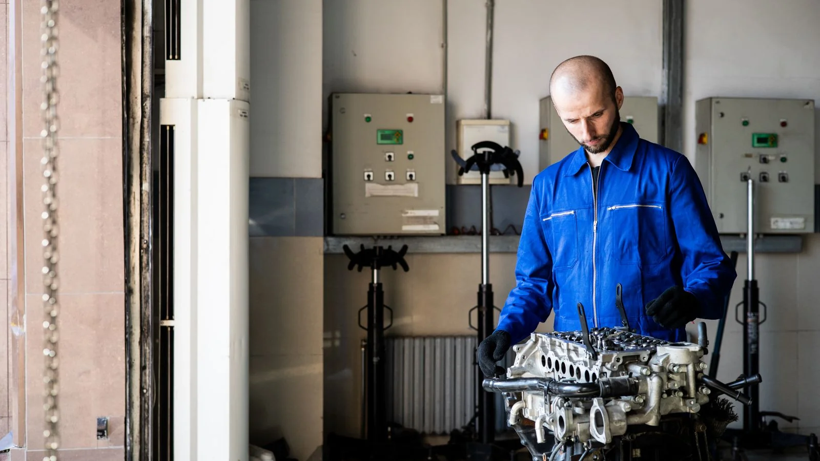 A repair technician in blue coveralls inspecting a machine, the work customers rate.