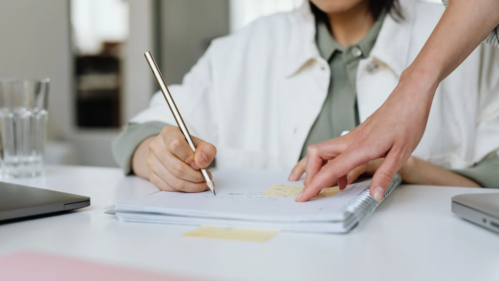Two people at a table taking notes, the audit step most coaches skip
