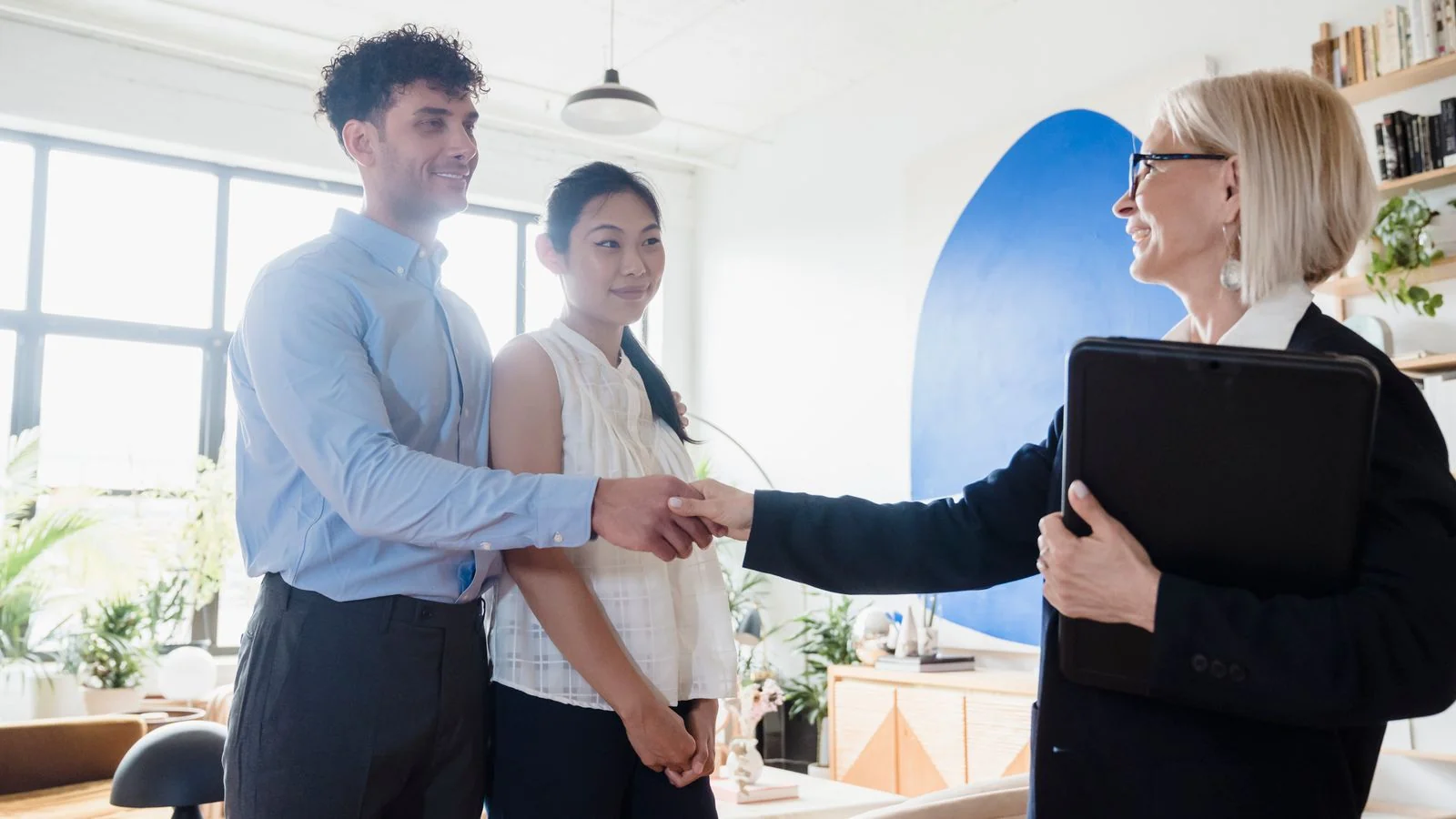 A home inspector shaking hands with a buyer couple outside a house after the inspection