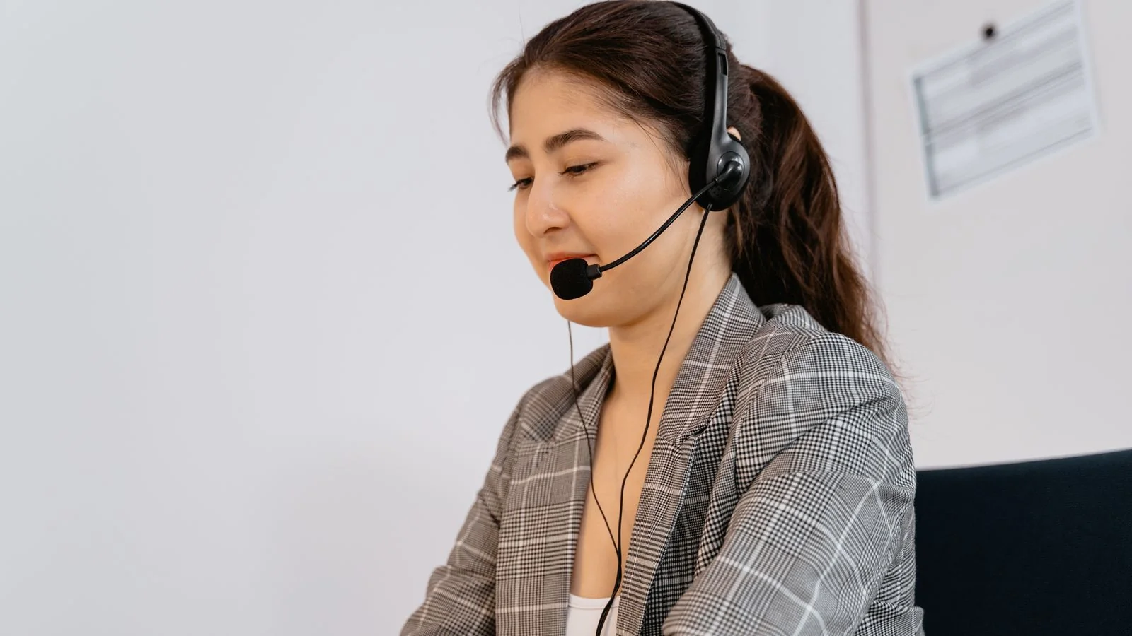 A customer service representative wearing a headset at a desk.
