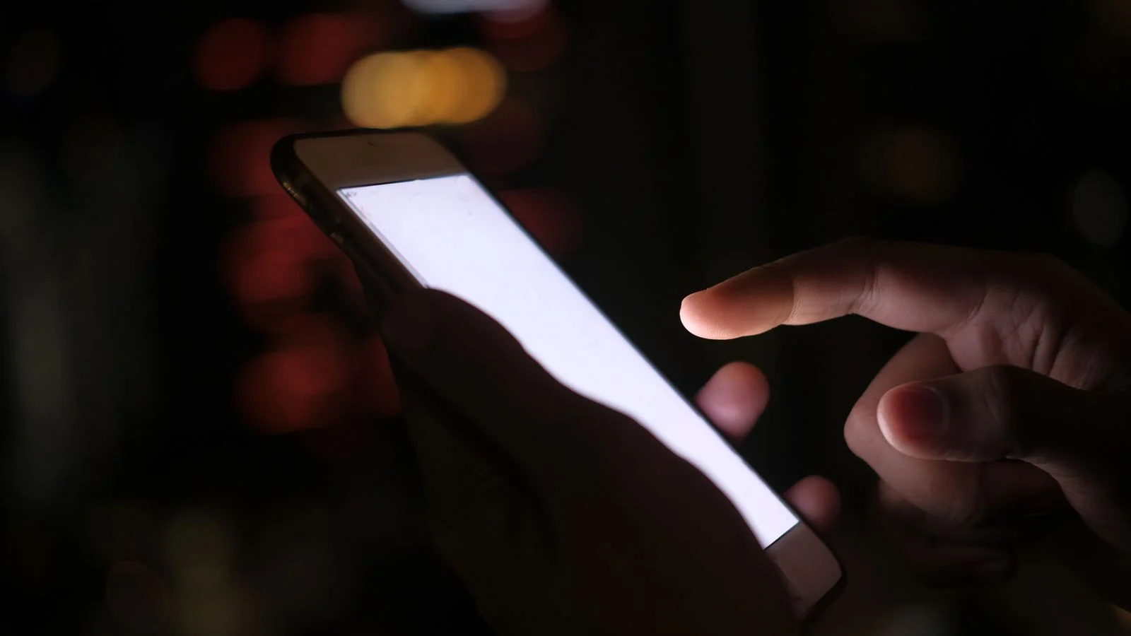 A hand lit by a phone screen at night, where a client writes the review you will read tomorrow
