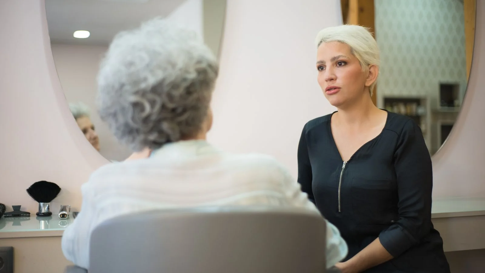 Two women talking in a salon with a mirror behind them, the private conversation that prevents a public review