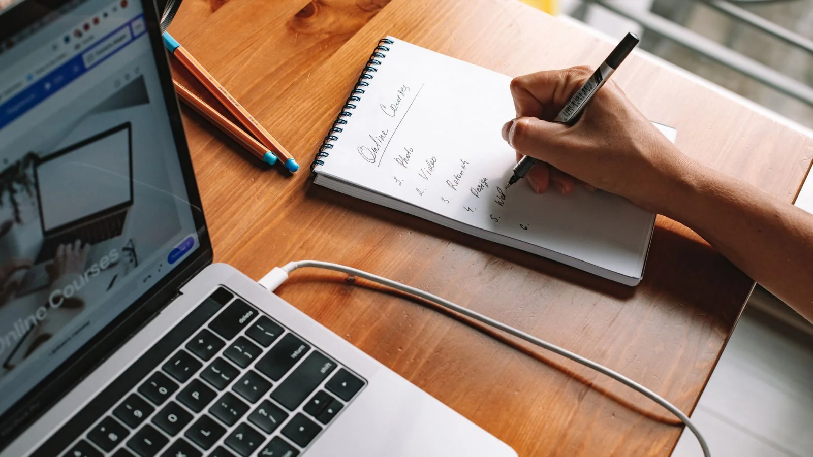 A person taking notes while researching courses on a laptop, the tab that decides the purchase